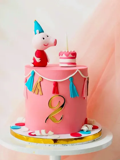 Here's another take on a Peppa Pig theme, this time with George. This pink buttercream cake is decorated with colourful tassels and a golden number '2' for a festive second birthday party.