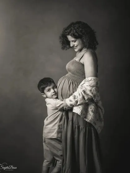 This black and white family maternity portrait captures the tender embrace between a mother and her son. The classic lighting and monochrome finish give the image a timeless, emotional quality.