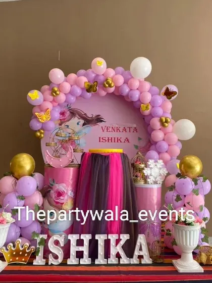 A beautiful naming ceremony decoration with a pink and gold color scheme and a custom backdrop.