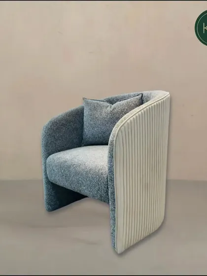 A full view of our contemporary armchair with a curved, enveloping back. The dual-fabric design adds visual interest, making it a sophisticated seating option for a lounge or office.