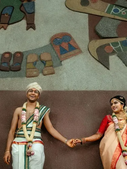 A wide shot of a couple posing against a unique, artistic wall after their wedding ceremony. We find creative backdrops for your portraits.
