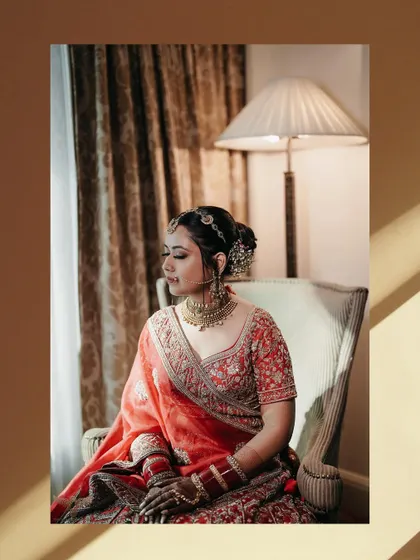 A beautiful window-lit portrait. The natural light and shadows create a soft, contemplative mood, highlighting the bride's calm demeanor before the ceremony.