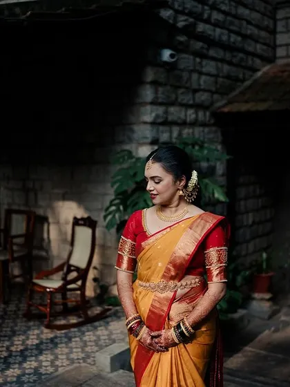 A bride in a yellow and red saree, captured in a moment of quiet contemplation against the backdrop of our heritage architecture.