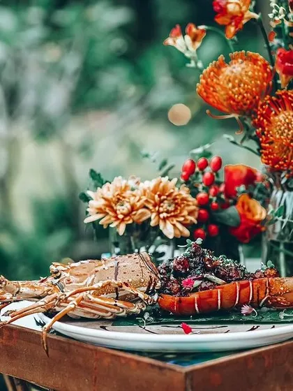 A stunningly presented lobster dish, surrounded by a vibrant floral arrangement.