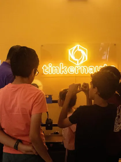 Students gather around to watch a 3D printer at work, captivated by the process of layer-by-layer creation.