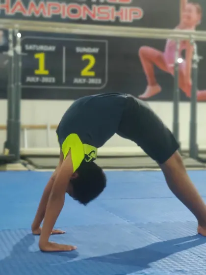 A young gymnast holds a strong back bridge. This is a fundamental move for improving back flexibility and shoulder strength, crucial for many gymnastics skills.