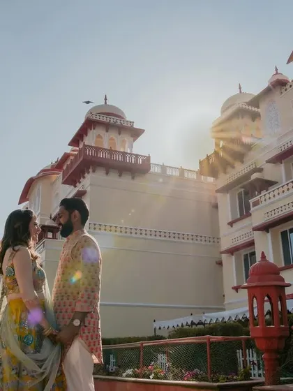 A romantic, sun-flared shot against the palace. The golden light, the birds in the sky, and the couple's loving gaze all come together to create a magical, fairy-tale moment.