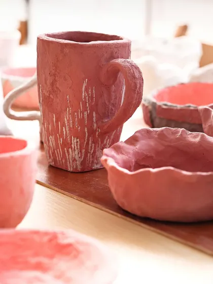 A collection of rustic, hand-built pieces in a deep pinkish-red. The rough textures and uneven surfaces are what make them so beautiful and full of character.