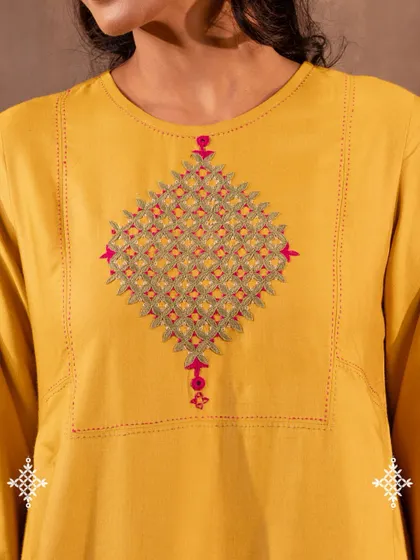 A detailed view of the Pakka hand embroidery on our Ruhani Yellow Pleated Kurta. Each stitch is counted and placed by hand, creating a resilient and sacred motif that carries the history of desert artisans.