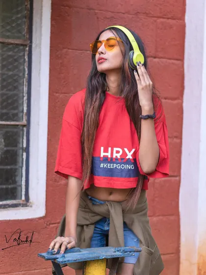 A lifestyle shot that's all about the vibe. The model is lost in her music, with the colorful top and cool sunglasses completing a look that is both trendy and authentic.