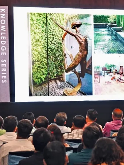 Gayathri Shetty presenting our firm's work at a Knowledge Series event, with images of our projects on the screen behind her.
