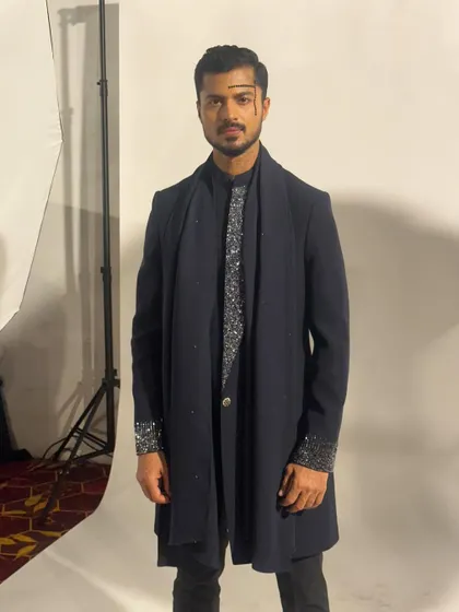 A studio-style shot taken backstage, showing the sharp silhouette of the designer's creation against a white background.
