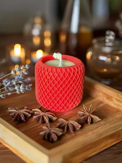 My Mesh Pattern candle in a bold red, set in a cozy, rustic scene. The textured holder is reusable, and the candle itself is made from 165g of scented soy wax for a long-lasting aroma.