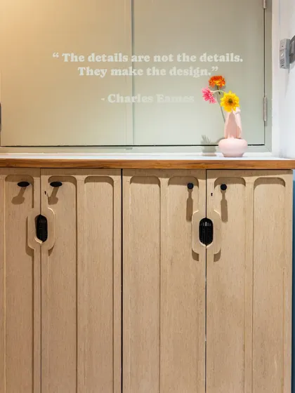 This entryway shoe rack is designed with slim, grooved doors and a marble top, providing essential storage while maintaining a sleek and modern look. The quote from Charles Eames reminds us that details make the design.