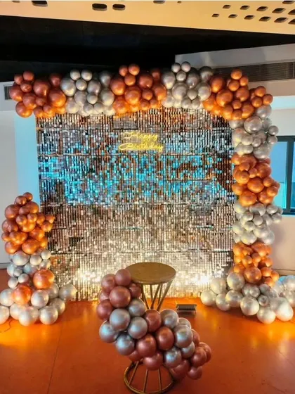 A sophisticated bronze and silver balloon arch over a silver sequin wall, perfect for elegant birthday parties or corporate events.