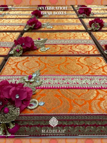 A display of multiple Celebration Bhaji Boxes, showcasing the beautiful brocade fabric, gota patti work, and floral embellishments. This is festive gifting at its finest.
