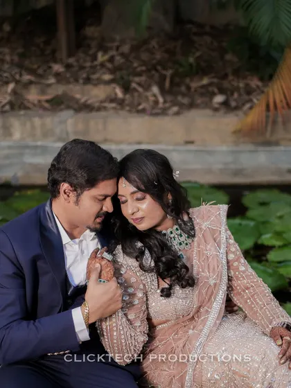 An intimate and tender close-up of a couple in formal Indian attire, sharing a quiet moment by a lily pond.