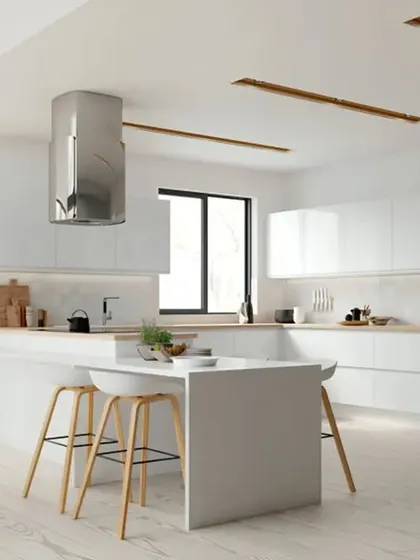 This all-white kitchen is the epitome of clean and bright design. The glossy handleless cabinets, minimalist island, and stainless steel chimney hood create a spacious, light-filled cooking environment.