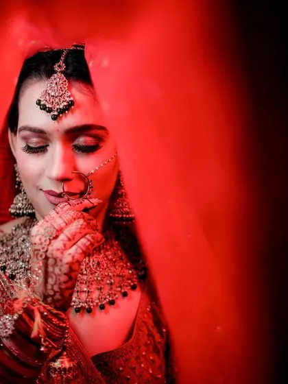 A close-up bridal portrait using a red veil and dramatic lighting. This technique creates a sense of intimacy and highlights the bride's features beautifully.