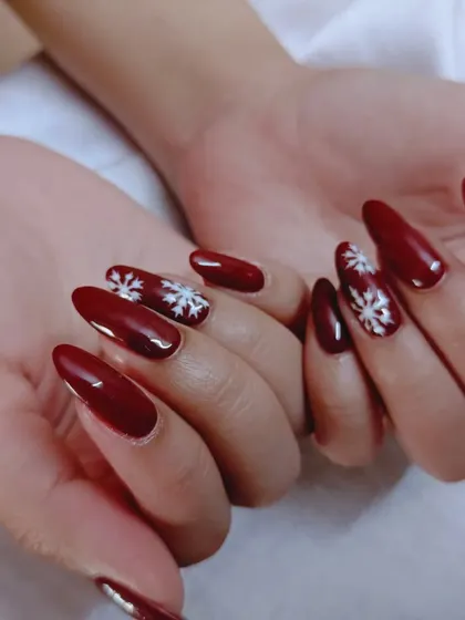 A festive winter set with a deep red polish and hand-painted white snowflakes.