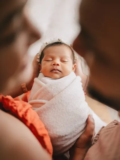 A beautiful close-up of the newborn, held securely by her parents. This perspective emphasizes how small and precious your baby is in your loving hands.