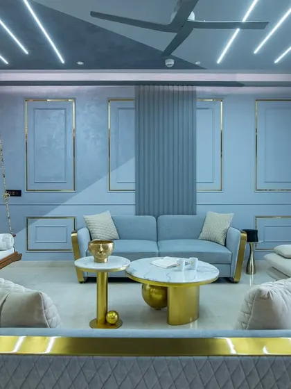 A full view of the living room at SNN Clermont, showcasing the cohesive blue and gold theme. The layout includes multiple seating areas and a traditional swing, making it a versatile space for relaxing and socializing.