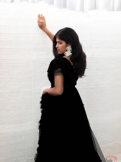 This black ruffle gown is a chic and sophisticated option for any photoshoot or event.