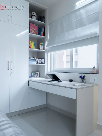 A minimalist and bright study nook integrated with a white wardrobe. The desk is placed by the window to take advantage of natural light, creating a perfect spot for reading and learning.