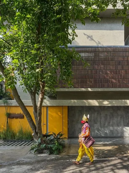 The street view of 'The Mantle', where clean lines, raw concrete, wood, and a bold yellow gate create a simple yet powerful facade.