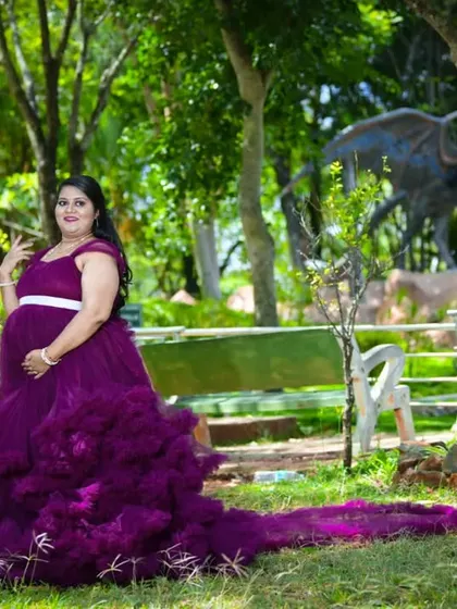A full view of the wine ruffle maternity gown in a park setting. The long train spreads out beautifully, creating a dramatic and memorable photograph.