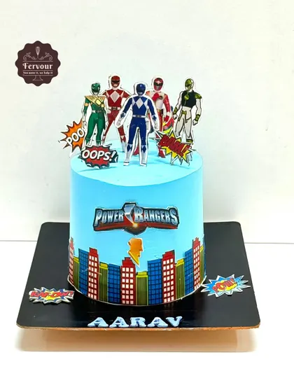 A Power Rangers-themed cake with the team assembled on top. The cityscape border and comic-book style "POW!" signs add to the action-packed feel of this chocolate truffle cake.