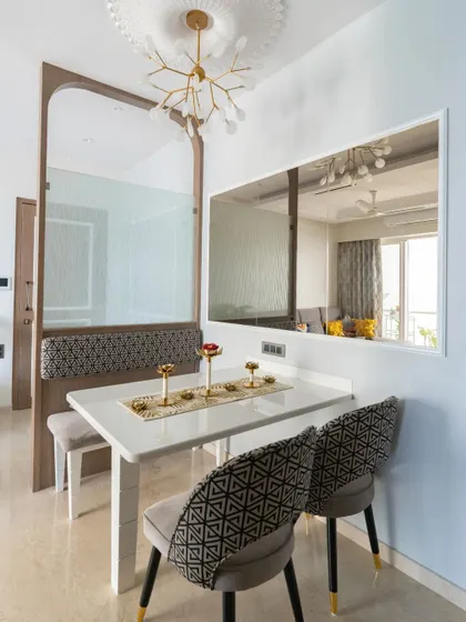 This compact space was cleverly transformed into a cozy dining nook. The design features bench seating to save space, a sleek white table, and a large mirror to make the area feel more open.