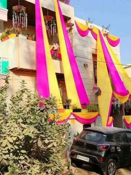 A bright and sunny view of a house decorated with long pink and yellow drapes for a daytime wedding event.