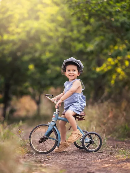 A vintage tricycle ride on a country path. The beautiful, soft light filtering through the trees makes this a perfect outdoor portrait.