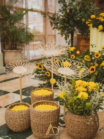 Baskets of fresh yellow flower petals ready for the Haldi rituals, displayed alongside whimsical paper flower stands.