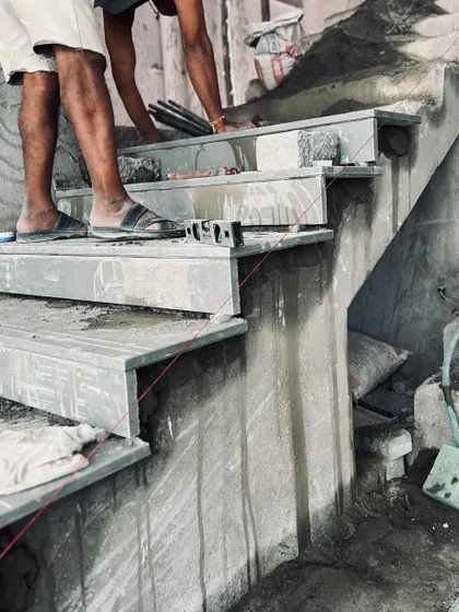 Meticulous craftsmanship in progress. Here, a skilled worker is carefully laying the stone for a floating staircase, ensuring every step is perfectly level and aligned.