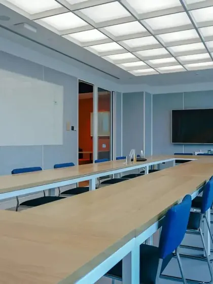 A side view of the boardroom, highlighting the whiteboard wall for brainstorming sessions and the professional AV setup for video conferencing.