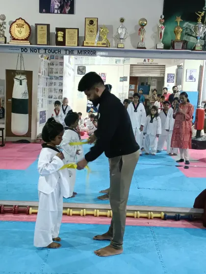 A very young student receives her yellow belt.