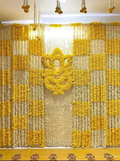 For a Haldi ceremony at home, I designed this full feature wall using a checkerboard pattern of yellow and white marigolds. The centerpiece is a Ganesha motif made entirely of fresh yellow marigold flowers, making it a perfect photo backdrop.
