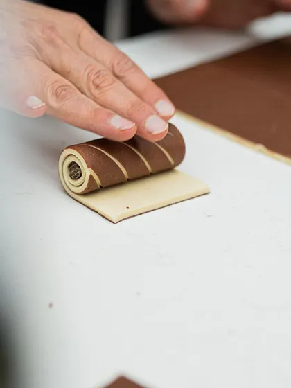 A chef rolls a bi-color dough log, a key step in making striped viennoiserie.