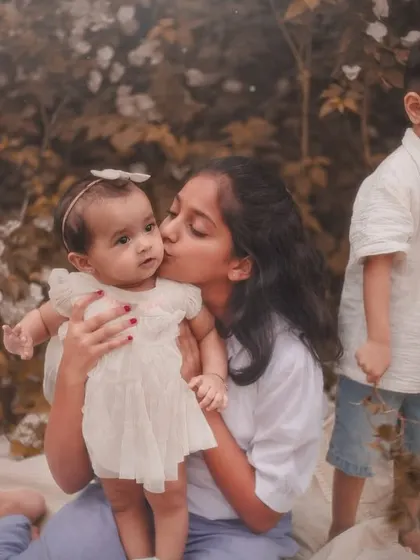 "Their love." A sweet kiss from an older sister to her baby sibling during a beautiful, warm-toned outdoor photoshoot.