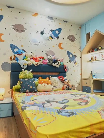 A child's imagination can take flight in this space-themed bedroom. The rocket and planet wallpaper is the star of the show, complemented by a house-shaped study nook and plenty of soft toys.