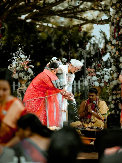 A serene wedding ritual in progress. We created a beautiful outdoor setup with a floral canopy, allowing the couple to perform their vows surrounded by nature and their loved ones.