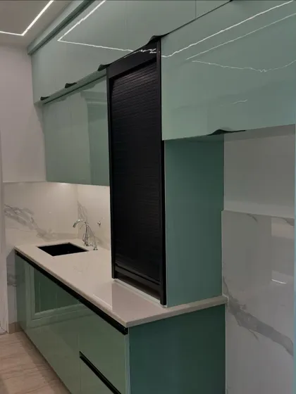 This modern kitchen features mint green back-painted glass shutters and a black rolling shutter for appliances. The look is fresh, modern, and easy to clean.