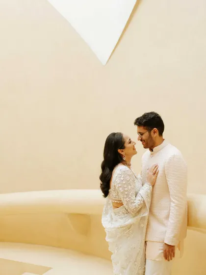 A sweet, interactive moment from a pre-wedding shoot. The couple's adoring gaze and the minimalist background put their connection at the forefront of the photograph.