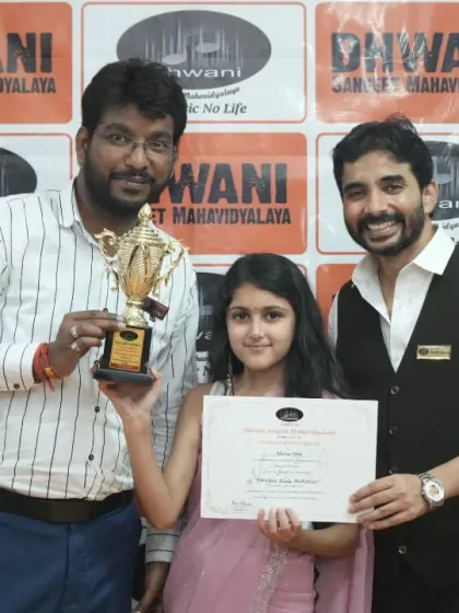 A teacher proudly presents a trophy to his accomplished student.