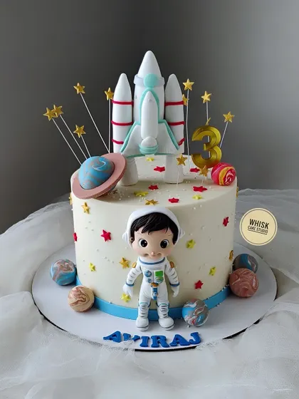 A space-themed cake for a third birthday. This non-fondant cake is decorated with a rocket ship, planets, and a cute, handcrafted astronaut figurine.