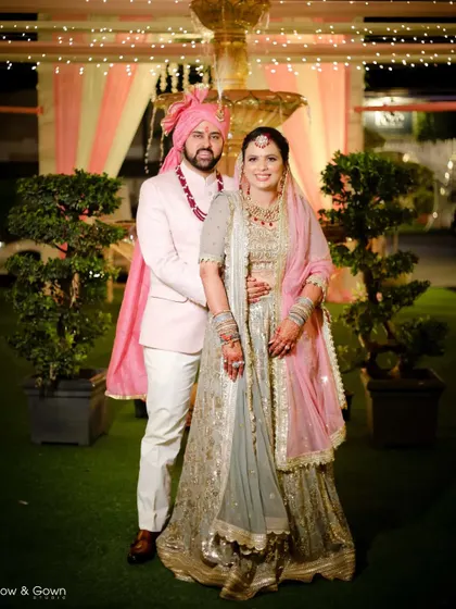 A full-length portrait of the couple on their wedding day. This shot showcases their beautiful outfits and the elegant outdoor decor of the venue.