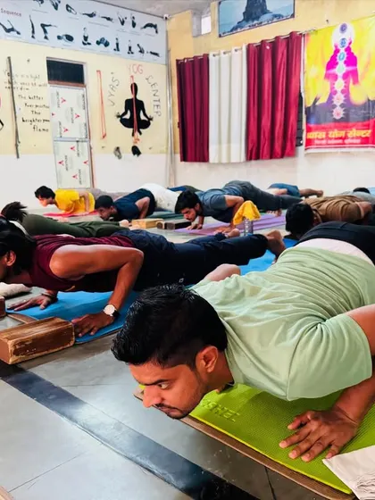 Students engage their core in a variation of Chaturanga Dandasana, using blocks for support. This builds the strength needed for more advanced postures.