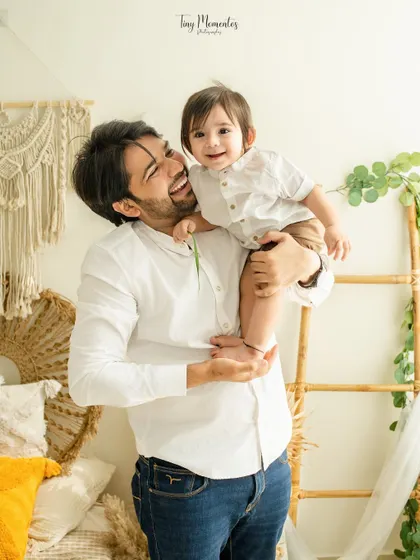 A playful peek over dad's shoulder. This candid moment is full of personality and showcases the fun-loving relationship between this father and son.
